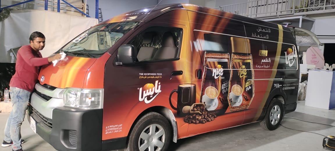 Installer applying a coffee brand wrap to a Toyota Hiace van