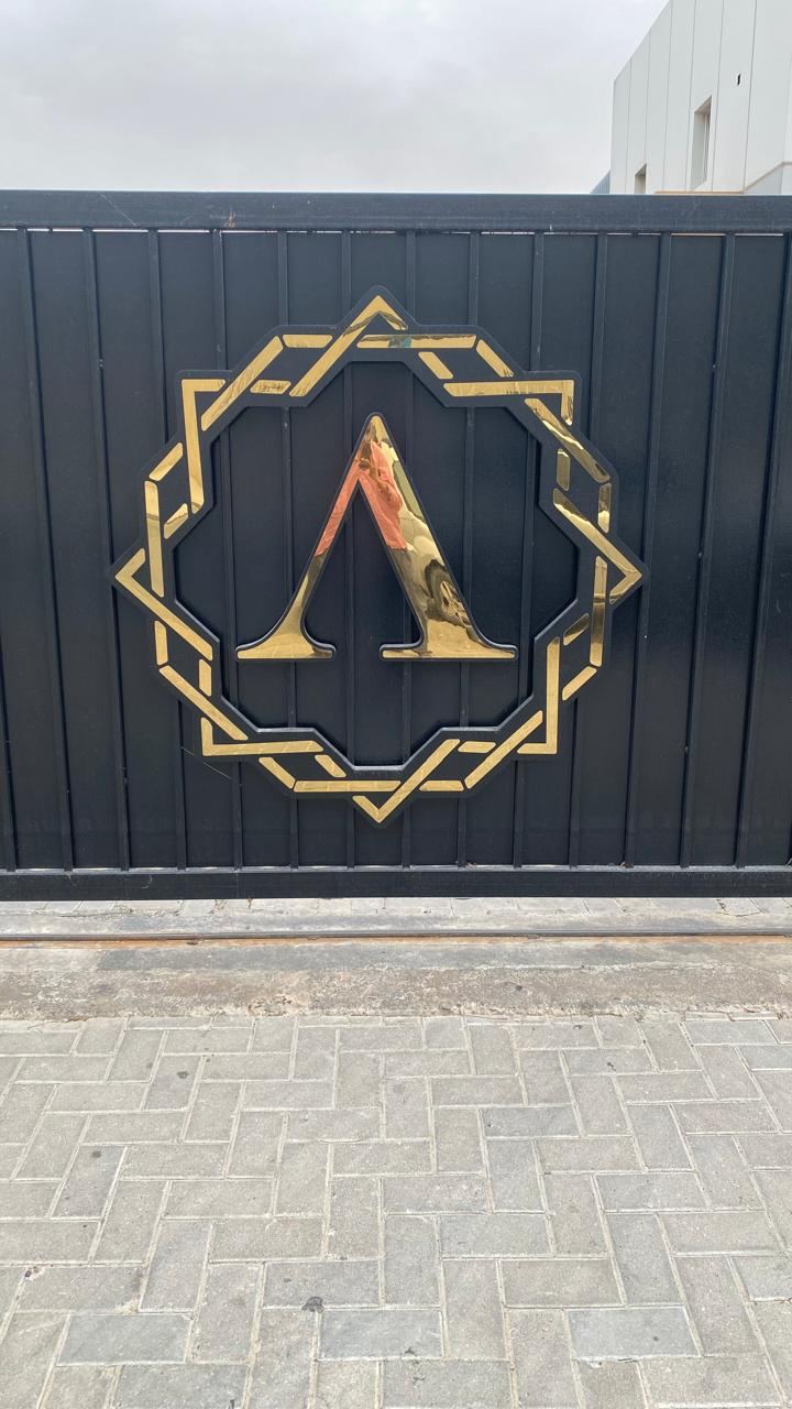 Gold 3D logo sign mounted on a black gate in Dubai